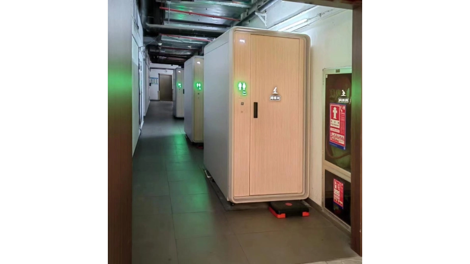 Compact public toilet modules installed along an indoor service corridor